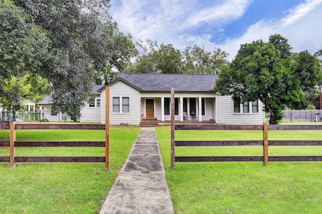 ranch-style house featuring a porch, roof with shingles, a fenced front yard, and a front lawn