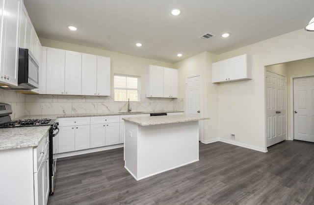 kitchen featuring decorative backsplash, stainless steel appliances, white cabinets, and a sink