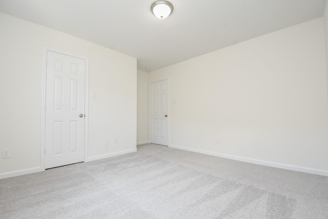 unfurnished room featuring baseboards and light colored carpet
