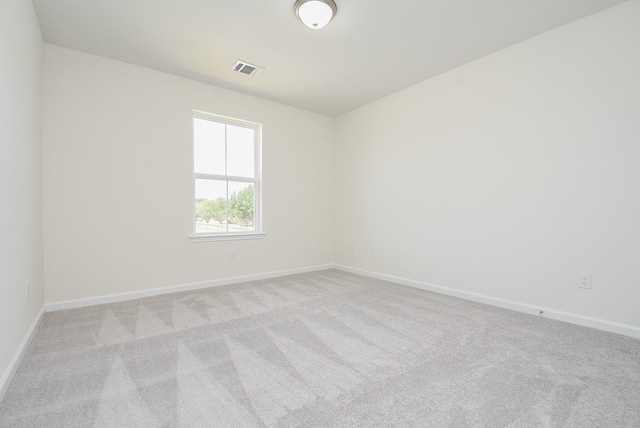 spare room featuring light colored carpet, baseboards, and visible vents