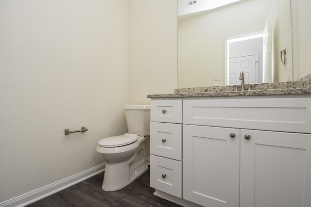 bathroom featuring toilet, wood finished floors, vanity, baseboards, and visible vents