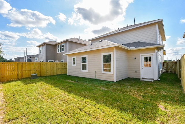 back of property featuring a shingled roof, a fenced backyard, and a yard