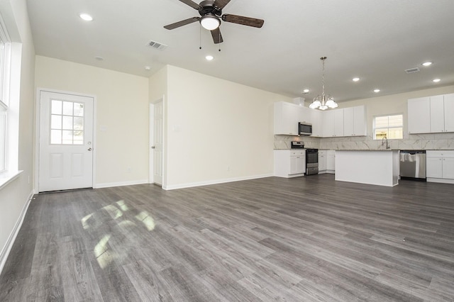 unfurnished living room with recessed lighting, visible vents, dark wood-style floors, and ceiling fan with notable chandelier