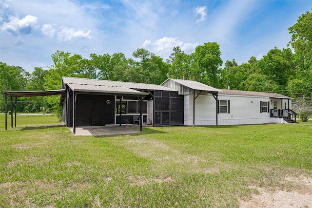 back of house featuring a sunroom, a yard, and metal roof