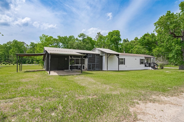back of house featuring a carport, a sunroom, and a yard