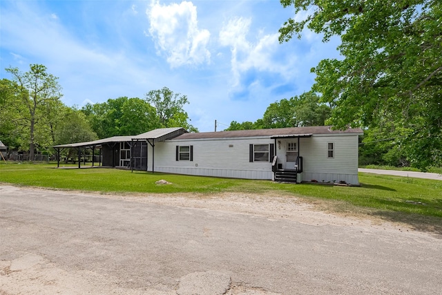 manufactured / mobile home featuring a carport and a front yard