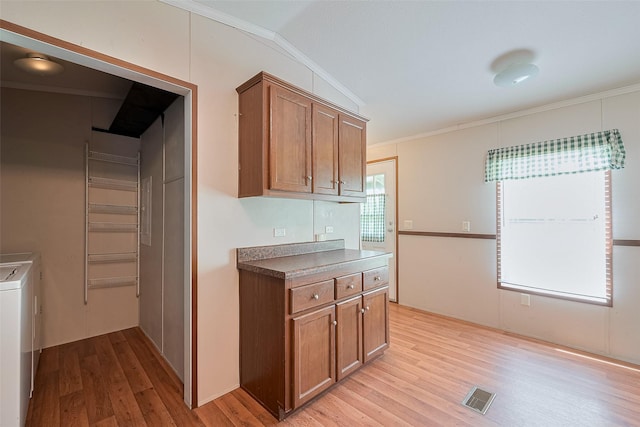 kitchen featuring light wood-style flooring, visible vents, brown cabinetry, and ornamental molding