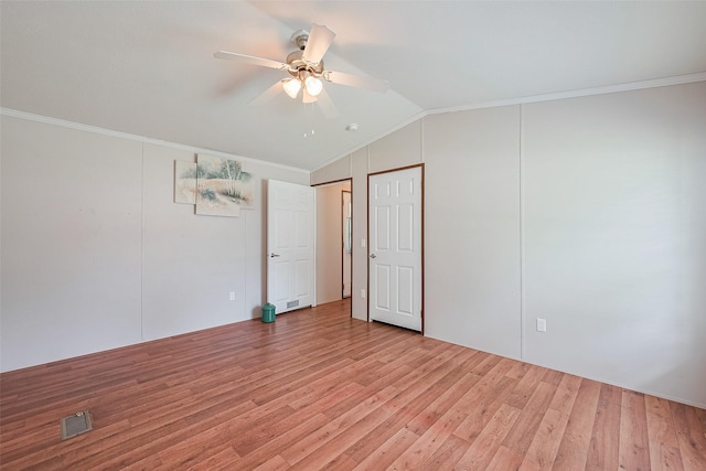 unfurnished bedroom featuring light wood-style flooring, vaulted ceiling, and crown molding