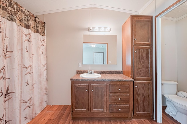 full bath with toilet, a ceiling fan, wood finished floors, vanity, and ornamental molding