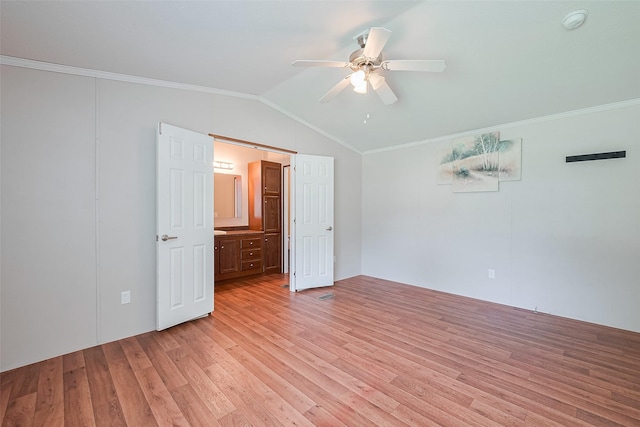 unfurnished bedroom featuring light wood finished floors, vaulted ceiling, a ceiling fan, ensuite bath, and crown molding