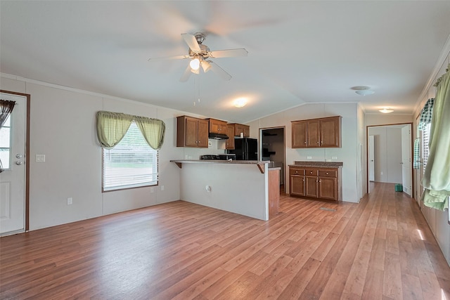 kitchen featuring light wood-type flooring, a peninsula, freestanding refrigerator, and brown cabinets