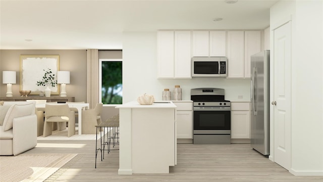 kitchen with light wood-type flooring, appliances with stainless steel finishes, a kitchen breakfast bar, and white cabinetry