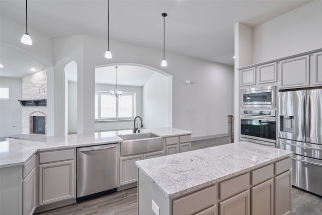 kitchen with appliances with stainless steel finishes, a center island, gray cabinetry, and a sink