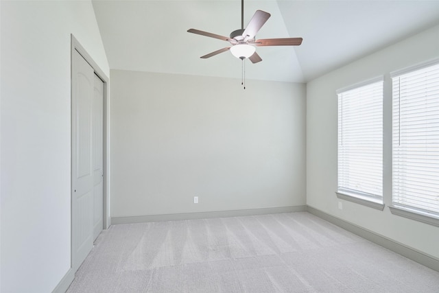 unfurnished bedroom with baseboards, vaulted ceiling, light colored carpet, and multiple windows