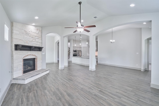 unfurnished living room with a ceiling fan, light wood-style flooring, visible vents, and a fireplace