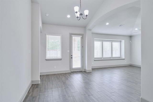interior space with an inviting chandelier, wood finished floors, visible vents, and baseboards