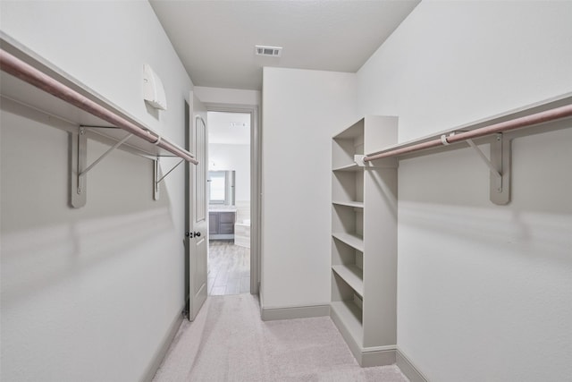 spacious closet featuring light colored carpet and visible vents