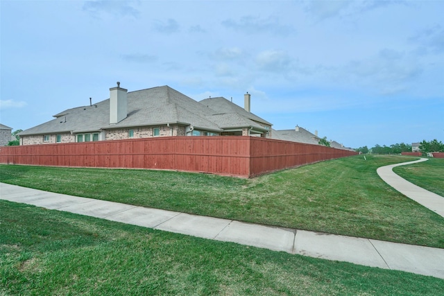 view of side of home with a lawn and fence