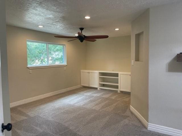 unfurnished room featuring baseboards, carpet flooring, a textured ceiling, and ceiling fan