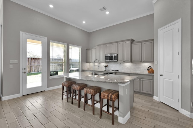 15534 Ponderosa Bend Dr, Cypress, TX 77429 - kitchen with a sink, stainless steel microwave, visible vents, decorative backsplash, and gray cabinets