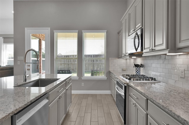 15534 Ponderosa Bend Dr, Cypress, TX 77429 - kitchen with stainless steel appliances, a sink, baseboards, backsplash, and light wood-style floors