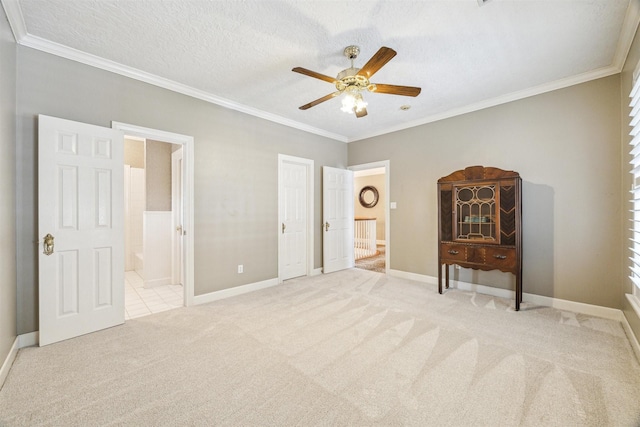 carpeted bedroom featuring connected bathroom, ceiling fan, baseboards, and ornamental molding