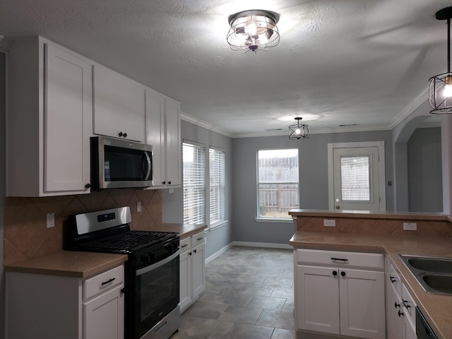 kitchen featuring white cabinets, stainless steel appliances, baseboards, and backsplash