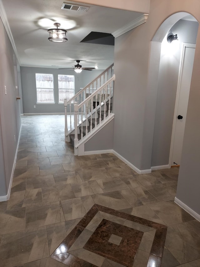 corridor featuring arched walkways, crown molding, visible vents, and baseboards