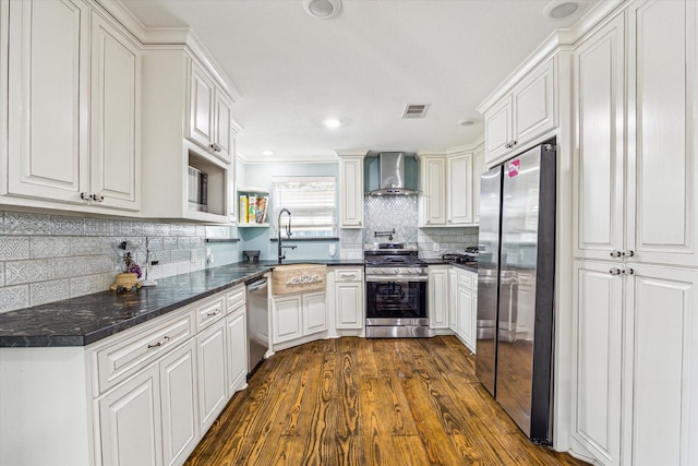 kitchen featuring wall chimney exhaust hood, stainless steel appliances, white cabinets, backsplash, and dark wood-type flooring