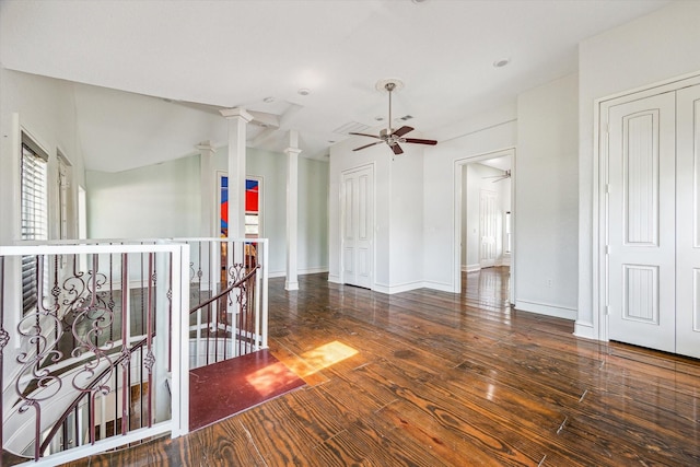 empty room featuring baseboards, a ceiling fan, wood finished floors, and decorative columns