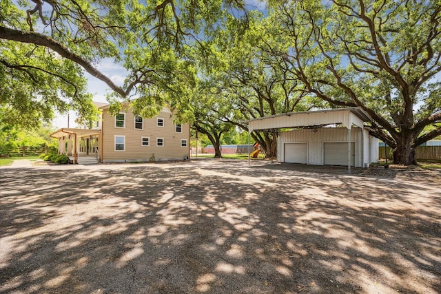 view of side of home featuring an outdoor structure, driveway, a garage, and fence