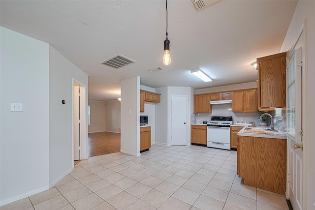 215 Pebble Canyon Ln, Dickinson, TX 77539 - kitchen featuring white range oven, brown cabinets, under cabinet range hood, light countertops, and light tile patterned floors