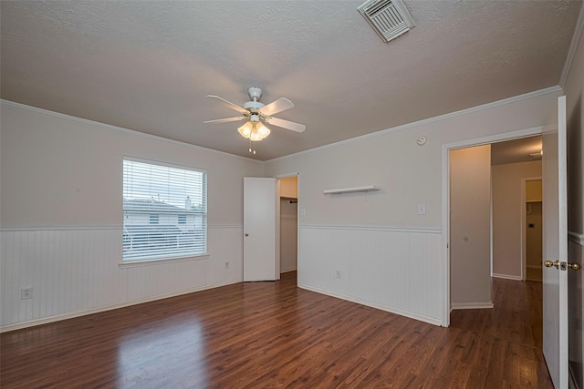 215 Pebble Canyon Ln, Dickinson, TX 77539 - empty room featuring ceiling fan, dark wood-style floors, a wainscoted wall, a textured ceiling, and crown molding