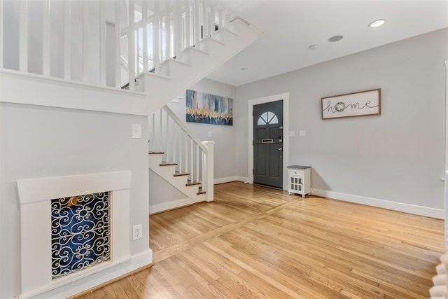 foyer featuring baseboards, recessed lighting, stairs, and wood finished floors