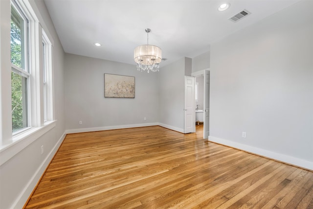 spare room featuring a notable chandelier, light wood-style flooring, recessed lighting, baseboards, and visible vents