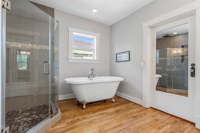 bathroom featuring wood finished floors, a freestanding bath, and a stall shower