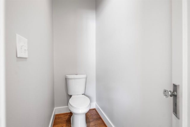 bathroom with toilet, baseboards, and wood finished floors