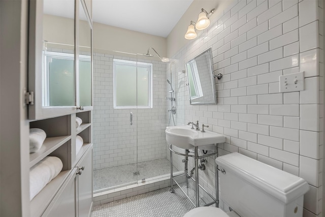 full bathroom featuring tile walls, a stall shower, a sink, tile patterned floors, and toilet