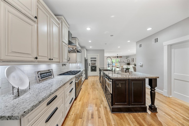 kitchen featuring light wood-style floors, decorative backsplash, stainless steel appliances, and visible vents