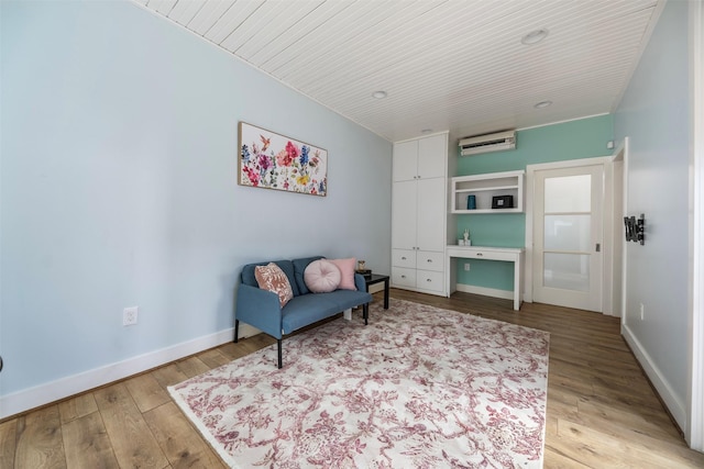 sitting room with wooden ceiling, baseboards, a wall unit AC, and light wood-type flooring