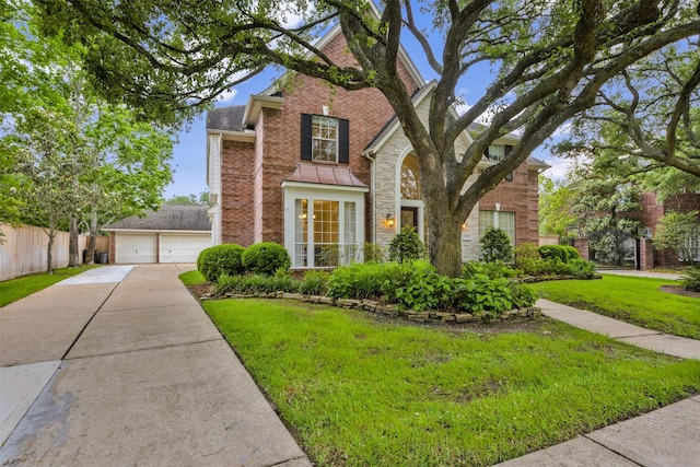 traditional-style house with a detached garage, brick siding, fence, a front lawn, and stone siding