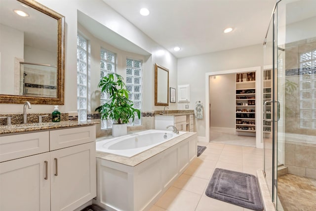 bathroom featuring a garden tub, two vanities, tile patterned floors, a shower stall, and a sink