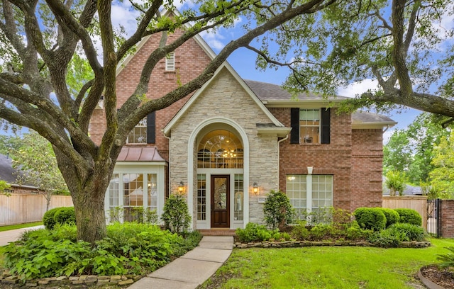 view of front facade featuring fence, stone siding, and a front lawn