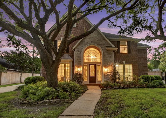 exterior space with a yard, brick siding, fence, and stone siding