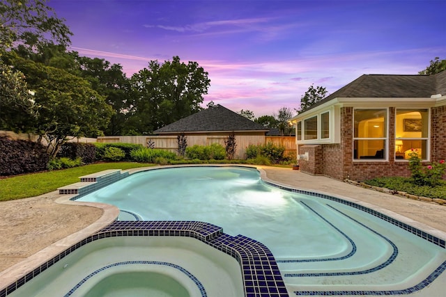 pool at dusk with an in ground hot tub, a fenced in pool, and a fenced backyard