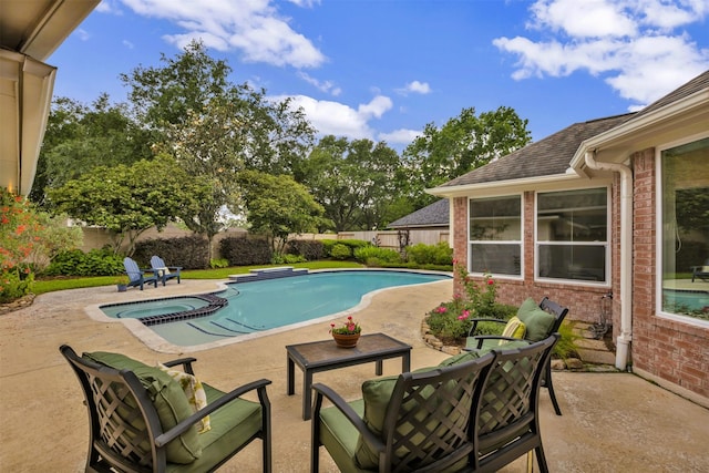 view of pool with a fenced backyard, a pool with connected hot tub, and a patio area