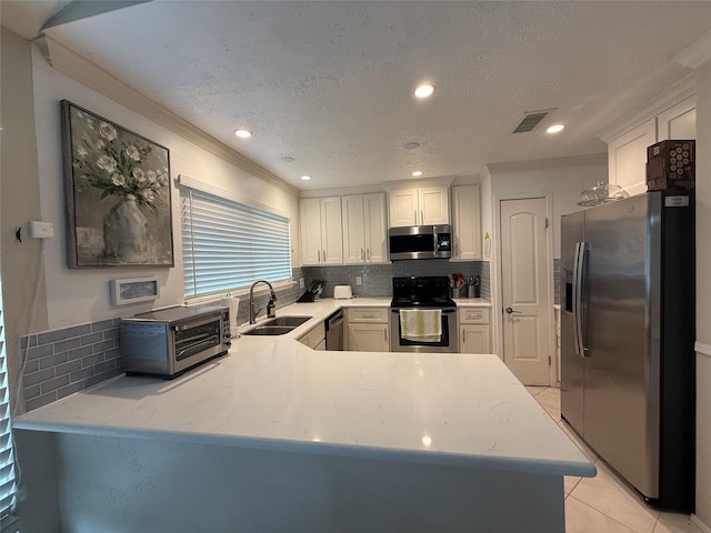 kitchen featuring visible vents, decorative backsplash, a toaster, a sink, and stainless steel appliances