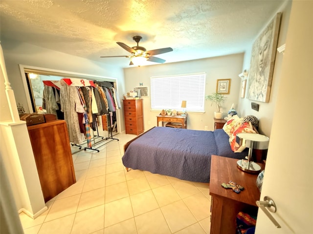 tiled bedroom with a ceiling fan, a closet, and a textured ceiling