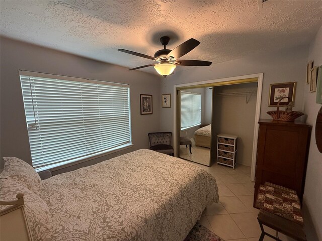 bedroom with a textured ceiling, ceiling fan, a closet, and light tile patterned flooring