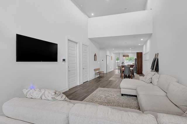 living room with recessed lighting, baseboards, a towering ceiling, and wood finished floors